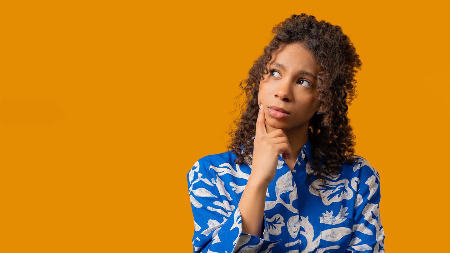 Woman thinking with right finger on her right cheek, looking to the right
