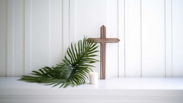 Cross, palm branch, and candle against white wall