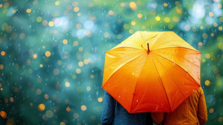 Orange umbrella shielding from vibrant rainy day bokeh, concept of protection and cheerfulness