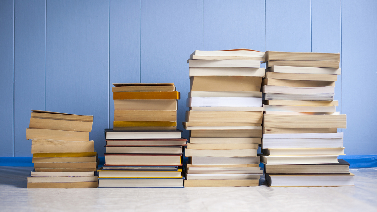 stacks of books in front of blue wall