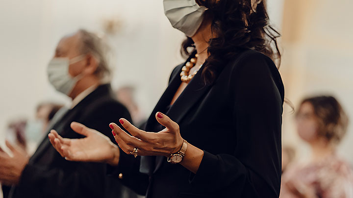 Woman worshiping in church with mask