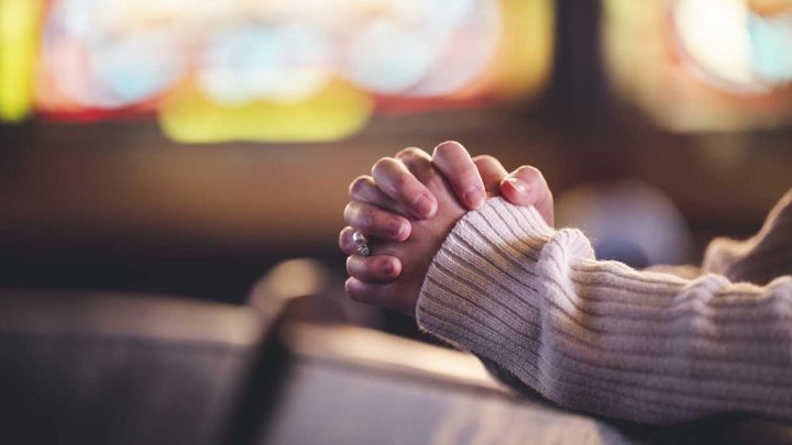 praying hands in a church pew